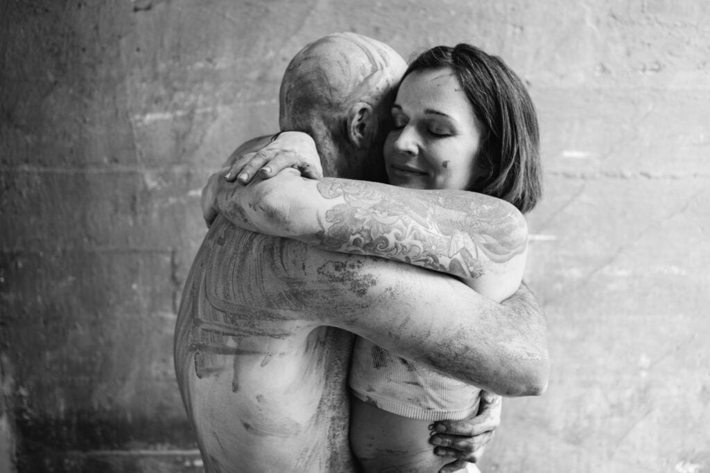 Jessica geeft Kristof een emotionele knuffel tijdens een fotoshoot met bodypaint in een industriële setting